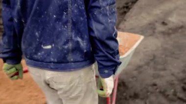 Bina üzerinde Adam sarı kum ile el arabası rulo