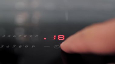 İnsanlar işaret parmağıyla elektronik ocaktaki düğmeye basıyorlar.