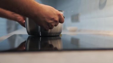 Adam seramik hob 'da tava hazırlıyor. Aşçı hazırlanıyor.