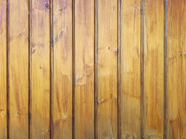 Sarı ahşap bir duvarın yakın plan görüntüsü doğal ahşap tahıl, düğümler ve dikey çizgiler gösteriyor. Yüzeyin kırsal ve hafifçe yıpranmış bir görünüşü vardır, arka plan, doku ve tasarım projeleri için mükemmeldir.