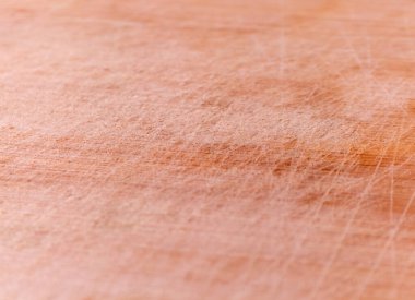 Açık kahverengi tahta kesme tahtasının detaylı makro görüntüsü ve görünür bıçak çizikleri. Resim, aşınmış, kullanılmış dokuyu, arka plan, mutfak temaları veya doğal ahşap yüzeyler gerektiren mutfak sunumları için idealleri sergiliyor..