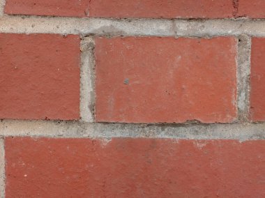 Sert yüzeyi ve çimento havan hatlarını gösteren kırmızı tuğla bir duvarın detaylı dokusu. Görüntü, arka plan, doku veya mimari kavramlar için uygun yapı malzemesi ve deseni vurgular.