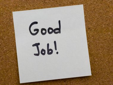 Motivasyon sözcüğünün mantar duyuru tahtasına yerleştirildiği el yazısı bir yapışkan not, bir çalışma alanı veya eğitim ortamında teşvik, tanıma ve olumlu geri bildirimi sembolize eder.