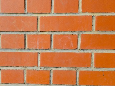 Yatay harç hatları olan kırmızı tuğlalı bir duvarın yakın görüntüsü. Tuğlaların yüzey dokusu ve açık bej harç eklemleri açıkça görülebiliyor ve tasarım için uygun endüstriyel ve kentsel bir yapı arkaplanı oluşturuyor.