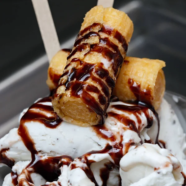 Roll ice cream is made by hand on the freezer. Sweet dessert made with biscuits and caramel syrup.