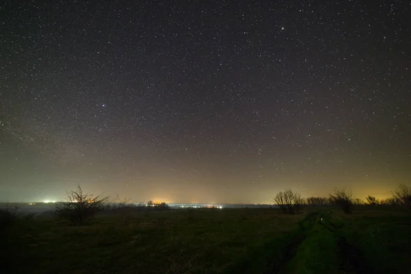 Stars in the night sky over a dirt road. Landscape photographed
