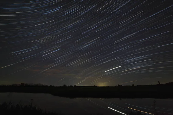 Trail of stars in the night sky with clouds