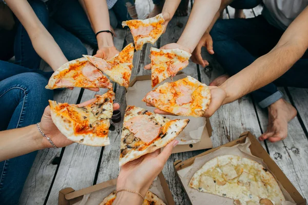 Friends eating pizza on the wooden pier