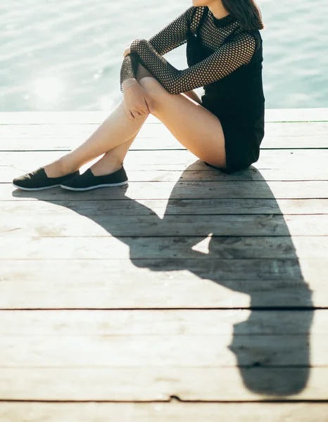 Einsames Mädchen sitzt im Sommer auf der Seebrücke — Stockfoto