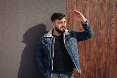 Duvarın yanında poz veren yakışıklı genç adam 