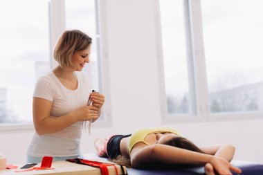 Göbeğinde kinesiyoloji bandı olan beyaz bir kız. Profesyonel bir fizyoterapist hastanın karnına esnek kineziyoloji bandı yapıştırıyor. Spor ve rehabilitasyon, kinesio tedavisi