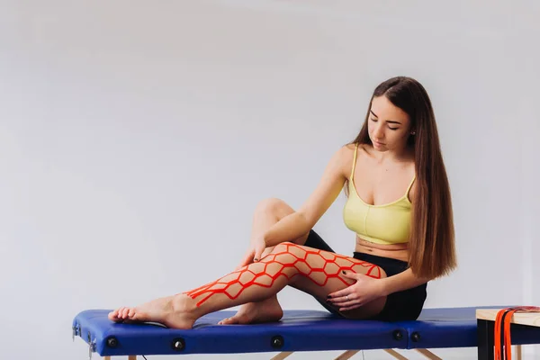 膝と脚に伸縮性のあるキニーシオテープをはめた可愛い女の子 腎臓学 理学療法 リハビリテーションの概念 — ストック写真
