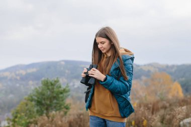 Genç gezgin kadın elinde dürbün tutuyor. 