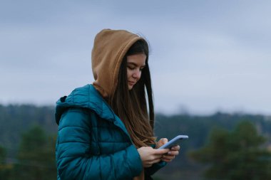 Açık havada akıllı telefon kullanan genç bir kadın.