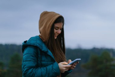Açık havada akıllı telefon kullanan genç bir kadın.