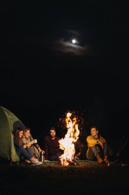 Gece vakti şenlik ateşinin önünde oturan yoldaşlar. 
