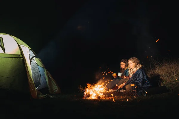 たき火の近くに座っている2人の女性旅行者 — ストック写真
