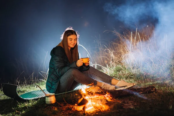 夜にたき火の近くに座っている女性 — ストック写真