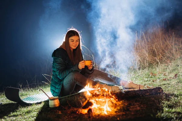夜にたき火の近くに座っている女性 — ストック写真