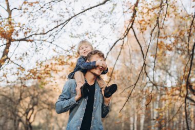 Mutlu baba ve oğul sonbahar parkında eğleniyor.