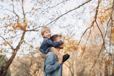 Mutlu baba ve oğul sonbahar parkında eğleniyor.