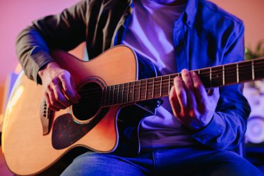 Yaratıcılık ve tutkuya dalmış rahat evinde akustik gitar çalarken orjinal müzik besteleyen genç bir müzisyen.