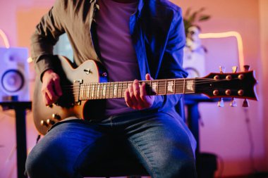 Yaratıcı enerjiyle dolu rahat bir kayıt stüdyosunda elektro gitar çalarak orijinal şarkılar besteleyen genç bir müzisyen.