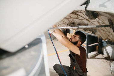 Bir kamyonun kaputunda çalışan yetenekli bir tamirci profesyonel bir garaj ortamında bakım ve onarım yapıyor.