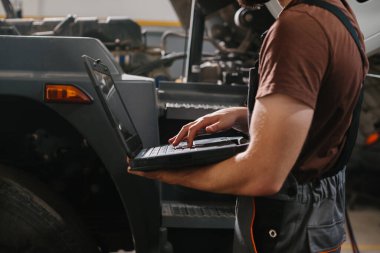 Profesyonel tamirci tamir atölyesinde ticari kamyonda elektronik tanı koyuyor. Modern teknoloji otomotiv bakımını karşılıyor