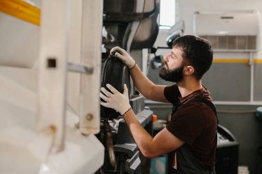 Eldiven takan profesyonel tamirci, özel atölyede hava filtresi değiştirip gerekli otomobil bakımını yapıyor.