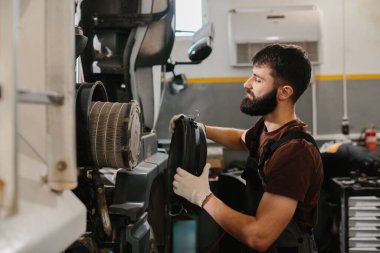 Tamir atölyesinin içindeki bir kamyon motorunun hava filtresini değiştirerek otomatik tamirci bakım yapıyor.