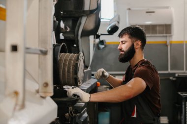 Eldiven takan oto tamircisi, yoğun bir tamirhanenin hava filtresini özenle değiştiriyor.