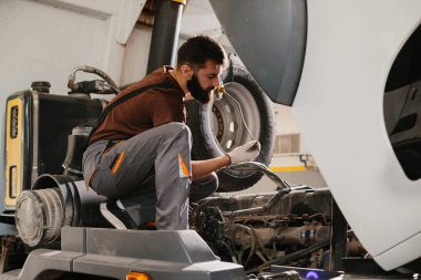 Otomatik tamirci garajda rutin bakım sırasında bir kamyonun motor yağı seviyesini kontrol ederek en iyi performansı ve güvenliği sağlar.