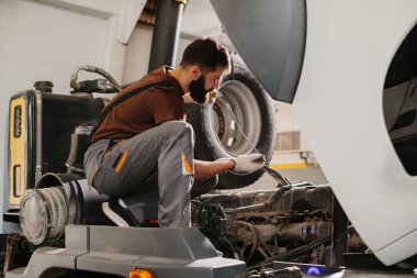 Otomobil tamircisi, garaj atölyesinde rutin bakım sırasında bir kamyonun motor yağı seviyesini denetliyor ve en iyi performansı sağlıyor.