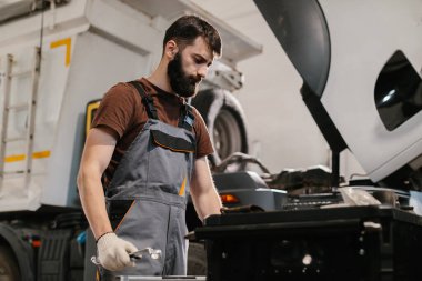 Otomobil tamircisi ingiliz anahtarı, bir garaj atölyesinde kamyon motoru üzerinde çalışıyor, bakım ve onarım yapıyor.