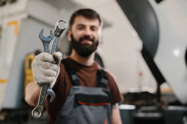 İngiliz anahtarı tutan sakallı bir tamirci kamyon bakım ve onarım konusunda uzmanlık gösteriyor. Endüstriyel araçlara ve makinelere odaklanın