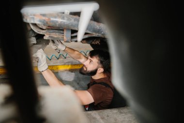 Tamirci, bir garajdaki kamyon parçalarının onarımına odaklanıyor, araç bakımında uzmanlık ve dikkat gösteriyor