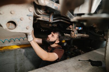 Bir kamyonun altında çalışan oto tamircisi, profesyonel bir garajda bakım ve onarım yapıyor.