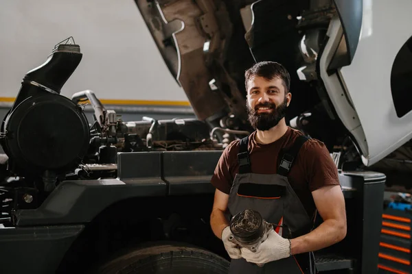 Kendine güveni tam bir tamirci. Profesyonel bir garajda motor tamirini başarıyla tamamladıktan sonra gülümsüyor.
