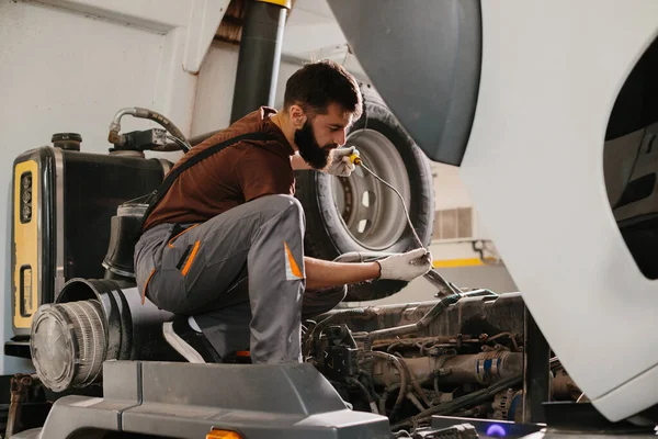Profesyonel tamirci bir atölyede bir kamyon motorunu tamir etmeye odaklanmış, otomotiv bakımı ve onarım alanında uzmanlık gösteriyor