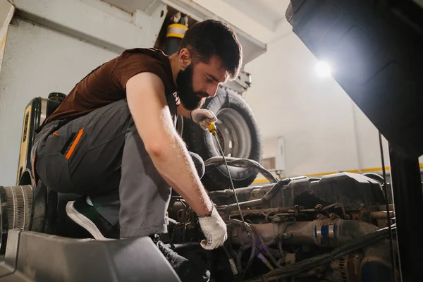 Bir kamyon motoru üzerinde özenle çalışan kendini işine adamış bir tamirci, bir garaj ayarında uzmanlık ve dikkat gösteriyor.