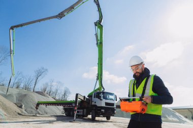 İnşaat işçisi çimento üretim tesisinde beton bir pompa kamyonu için ustalıkla uzaktan kumanda kullanıyor.
