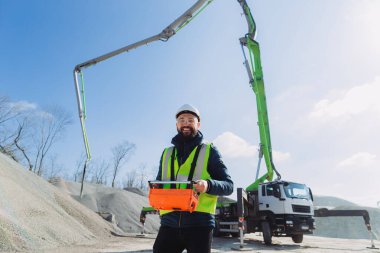 İnşaat işçisi, güneşli bir günde üretim tesisinde beton pompa kamyonu için uzaktan kumanda kullanıyor.