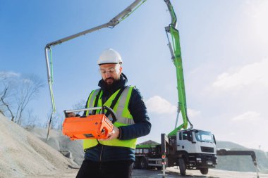 Beton üretim tesisinde beton pompa kamyonu için uzaktan kumanda kullanan inşaat işçisi