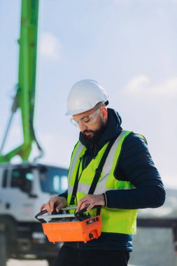 Beton bir üretim tesisinde beton pompa için uzaktan kumandalı güvenlik ekipmanı kullanan inşaat işçisi