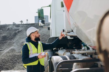 İnşaat mühendisi, beton üretim tesisinde çimento karıştırıcı kamyonu inceliyor.