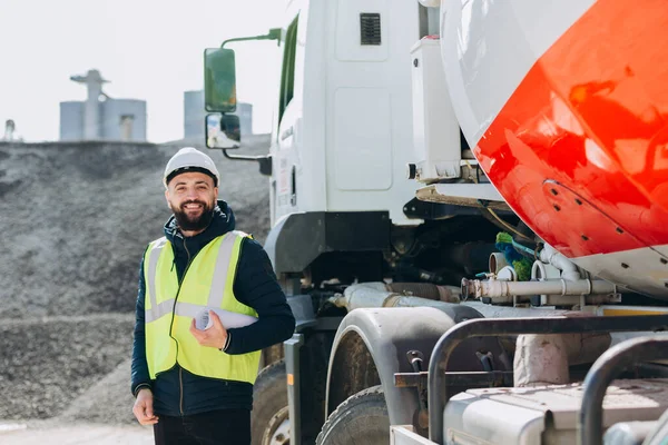 İnşaat mühendisi beton üretim tesisinde çimento kamyonunun yanında proje tutuyor, endüstriyel beton üretimi