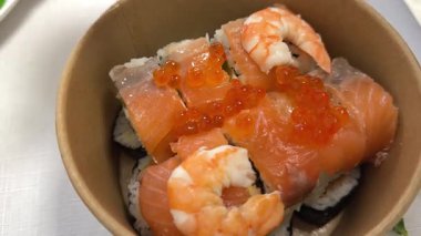 A sushi chef puts a fried roll into a paper box for delivery. sushi in cardboard box delivery