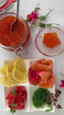 Kırmızı balık havyarı limonlu wasabi zencefilli deniz yosunu chuka kırmızı balık masası çiçeklerle süslenmiş ve mikro yeşil limon, eko ve doğal beslenme gıdalarıyla süslenmiş. 4 bin. Yüksek kalite 4k görüntü