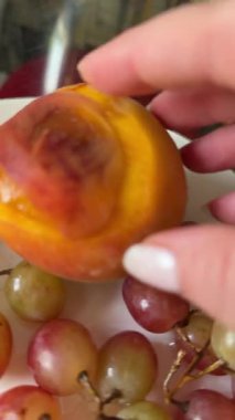 rotten spoiled peach near grapes on a plate of midges. High quality 4k footage